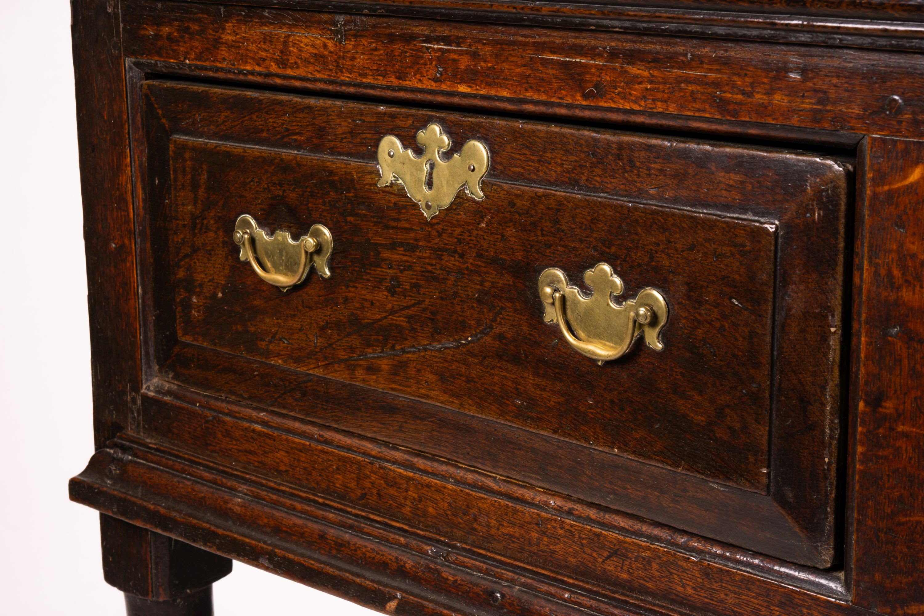 An 18th century oak low dresser on pole turned legs and pad feet, length 198cm, depth 53cm, height 88cm